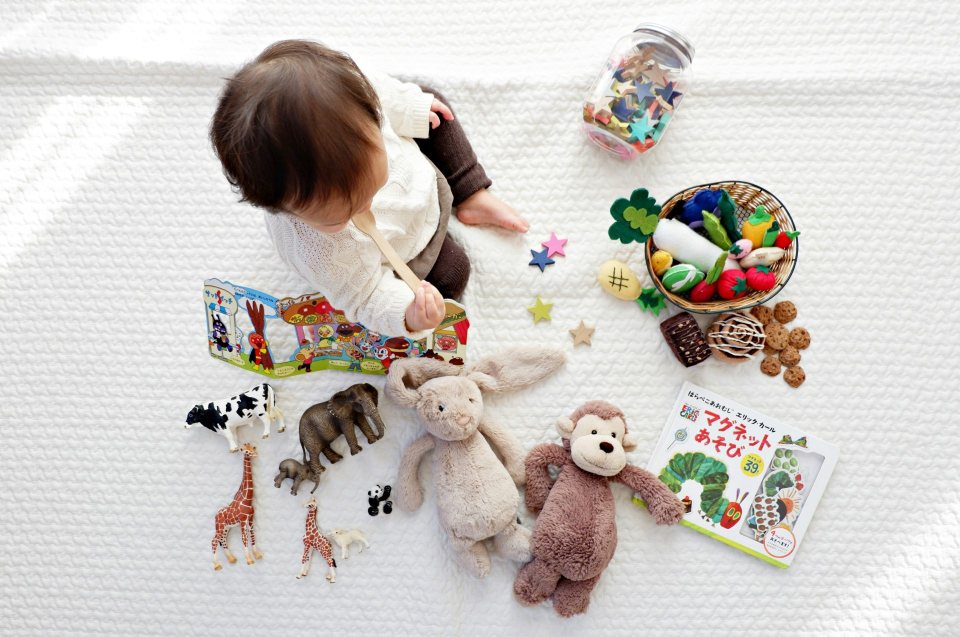 Kind spielt mit Spielzeug und Buch
